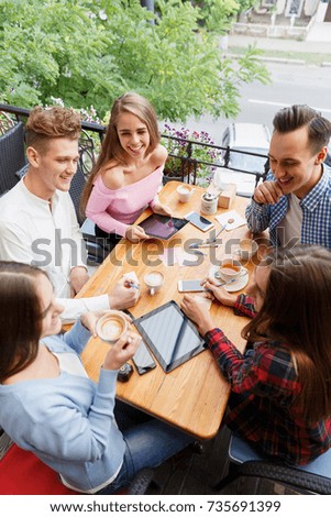 Young cheerful friends chatting at the cafe on the outdoors background. Friendship concept.