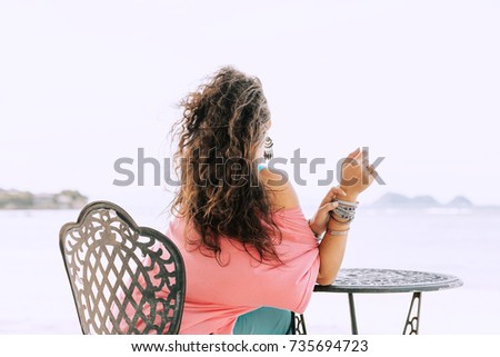 beautiful cheerful young woman sitting in cafe on the beach