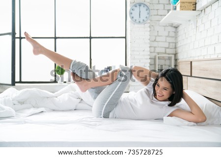 Asian women exercising in bed in the morning, she feels refreshed. Royalty-Free Stock Photo #735728725