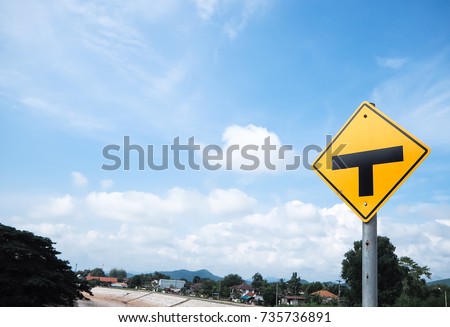 Travel and journey concept.T-Junction sign.On clear blue sky and white windy cloud,cityscape and riverside as background.Copy space for text on left.