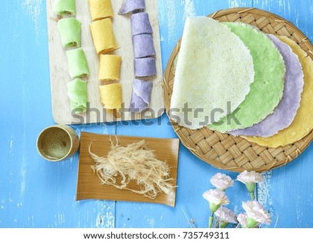 Thai dessert is called Roti Sai Yai, many colors are laid on blue wooden floor.