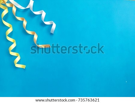 Closeup white,yellow & orange curly ribbon on light blue background.Colorful curled ribbon on blue background.The concept of party accessories, Birthday party.Top view with Copy space.Selective focus.