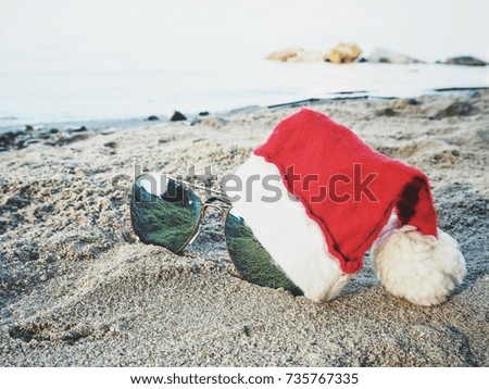 Sun glasses on the beach with christmas hat
