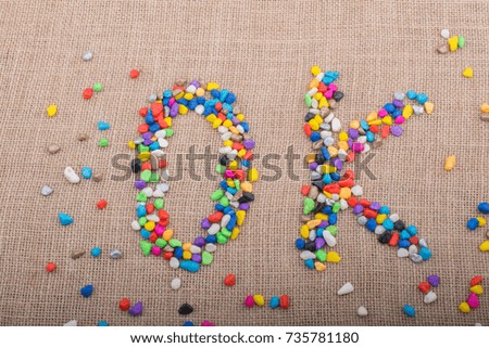 Colorful pebbles form the word OK on canvas ground