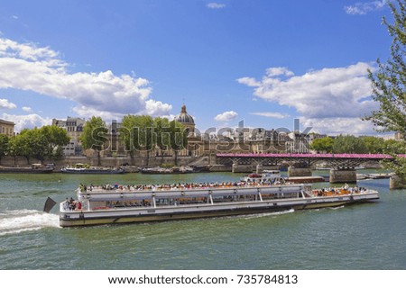Large pleasure boat sailing along river Seine in Paris, France with a Bridge of Arts (Pont des Arts ) on the background