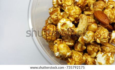 Caramel popcorn and nuts in cup on white background.