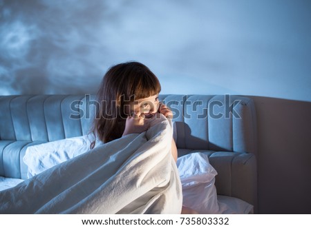 Night terrors of the child. Fear of the dark. The baby on the bed at night. An empty space to insert text. Royalty-Free Stock Photo #735803332