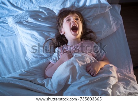 Night terrors of the child. Fear of the dark. The baby on the bed at night. An empty space to insert text. Royalty-Free Stock Photo #735803365