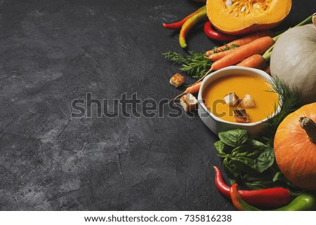 Creamy pumpkins soup with vegetables over black texture. selective focus. copy space