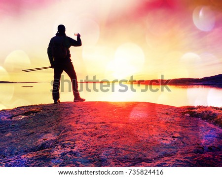 Lens defect. Tourist guy taking pictures of amazing sea landscape on mobile phone digital camera. Hiker stay on a rock near the smooth ocean. A beautiful sunset light create background with copy space