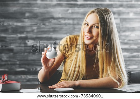 Portrait of happy young woman drinking coffee at modern office desk. Morning, drink, beverage concept 