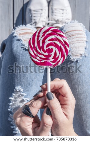 Red lollipop in a trendy fashionable woman hand, top view. Fashion, happy life in the city, happiness concept. 
