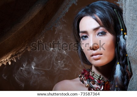 American Indian fortune teller looking from a tent with a smoke - studio photo with professional makeup