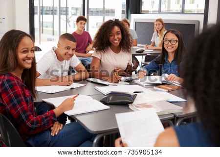 High school kids looking to teacher sitting at their desk Royalty-Free Stock Photo #735905134