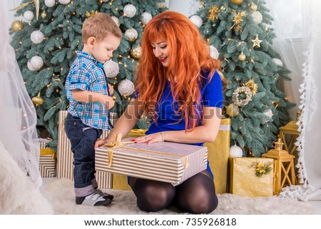 Happy mother and her little child surrounded with Christmas decorations. Opening presents