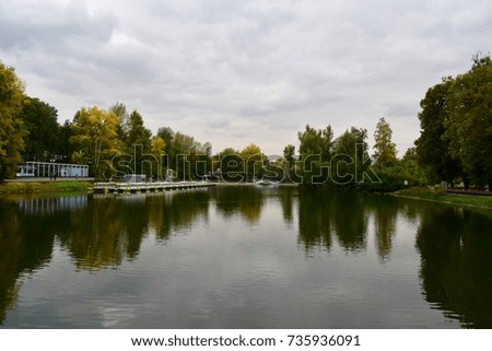Reflection of trees on water on a cloudy day in autumn in Gorky Park, Moscow, Russia.