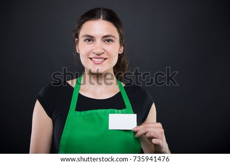 Smiling girl seller holding visit card with copy text space on dark background