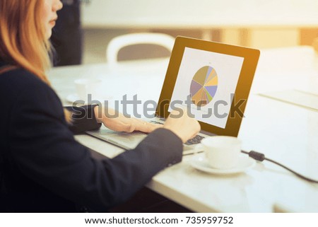 Close-up businesswoman using laptop computer working with statistics and cup of coffee on table. 
