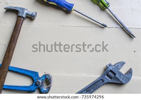 different hand tools on a wooden white background viewed from above