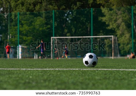 Traditional black and white soccer ball on green grass playground. Football game, Outdoors activity, summer sunny day.