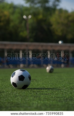Traditional black and white soccer ball on green grass playground. Outdoors activity, summer sunny day.