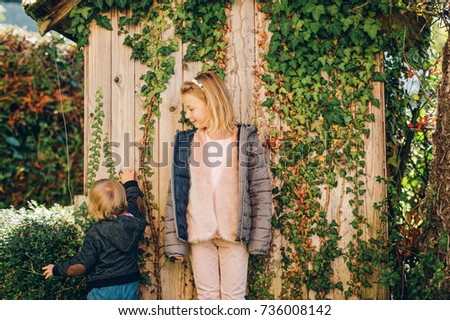 Two kids playing together in beautiful autumn garden, wearing warm jackets, family time