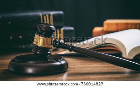 Law gavel on a wooden desk, law books background