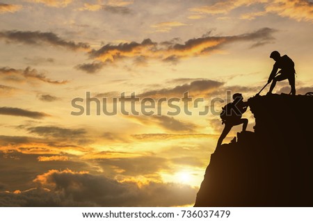 Male and female hikers climbing up mountain cliff and one of them giving helping hand. People helping and, team work concept.  Royalty-Free Stock Photo #736037479