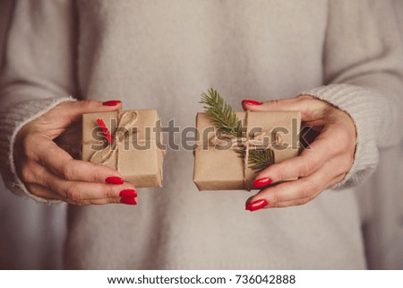 Woman's hands hold christmas or new year decorated gift box. Toned picture.