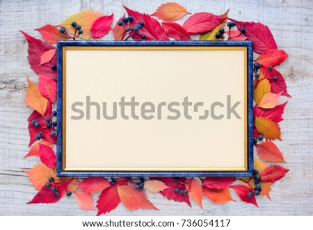 Autumn leaves composition with picture frame on a wooden background. Top view. Space for your text.