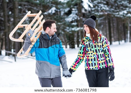 Couple having fun on winter sunny day, enjoy together in sledding