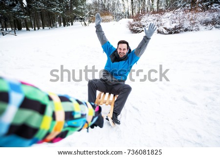 Smiling happy couple walking through the forest and enjoy with sleigh
