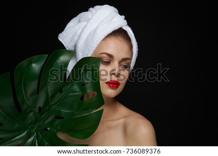 Perfect beauty woman face with a palm leaf on a black background
