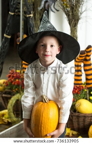 Halloween Small boy in spider web hat at striped socks. Holiday and celebration. Party and traditional food. Halloween child with happy face. Kid with orange pumpkin in witch hat.