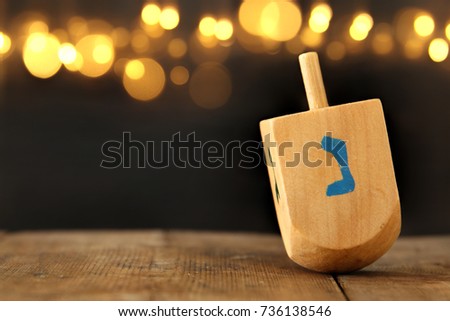 Image of jewish holiday Hanukkah with wooden dreidel (spinning top) and gold lights on the table