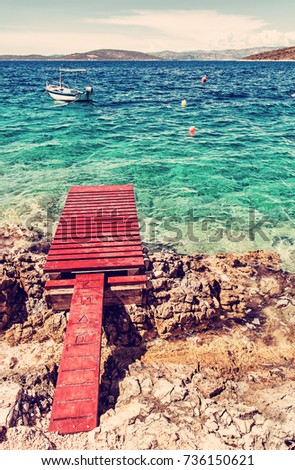 Beautiful Mediterranean sea, Solta, Croatia. Summer vacation. Springboard, turquoise water and little boat. Red photo filter.