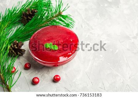 Red sauce or jam with christmas decoration over grey background with copy space