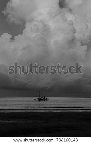 Boats fishing in the sea against the backdrop of a huge rain clouds look awesome black and white picture.