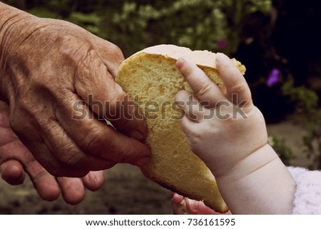 An old grandmother gives a piece of bread to a little girl