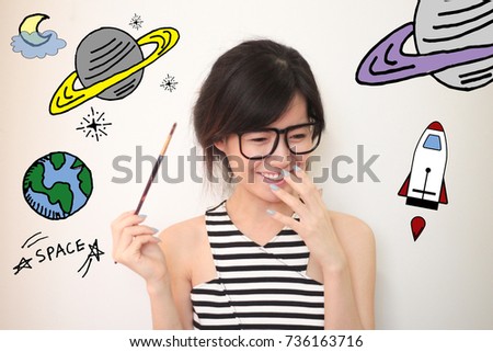 Young Asian woman holding brush painting with stars and space  illustrator doodles - space and science concept