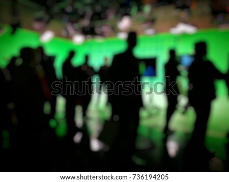Out of focused and silhouetted people in green screen studio, behind the.scene of pre production of news broadcasting.