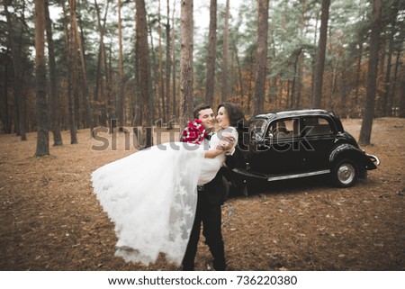 Beautiful wedding couple posing near splendid retro car