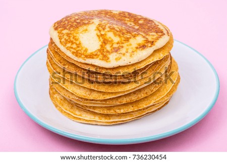 High stack of fried pancakes on pink background. Studio Photo