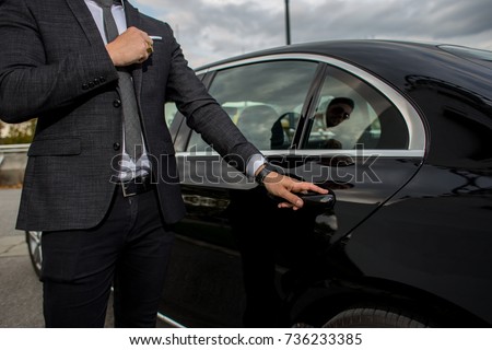 Man opening a black car limousines door Royalty-Free Stock Photo #736233385