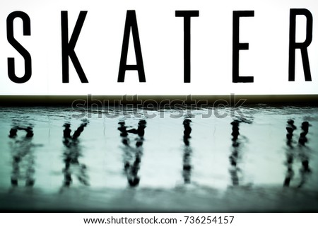 A light up board displays the phrase SKATER reflected on wet slate