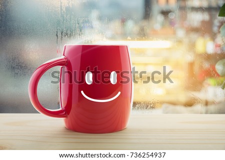 Red mug of coffee with a happy smile, Steaming red coffee cup on a rainy day window background, Good morning or have a happy day message concept Royalty-Free Stock Photo #736254937