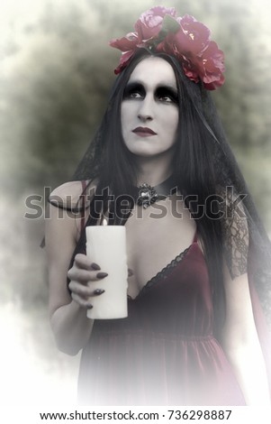Portrait of a girl in makeup and a dress for halloween with a candle in her hand.