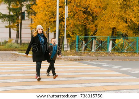 Mom and his child cross the road in the city on a pedestrian cro