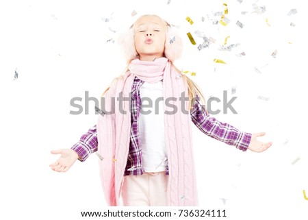 Portrait of little girl wearing scarf and winter ear muffs on white background
