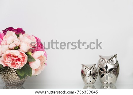 Bouquet of pink peonies on the shelf with ceramic owls
